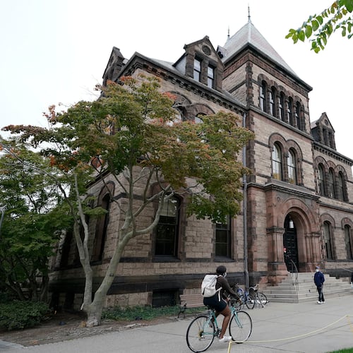 FILE - Passers-by walk and ride along a path on the campus of Brown University, in Providence, R.I., Monday, Oct. 12, 2020. (AP Photo/Steven Senne, File)