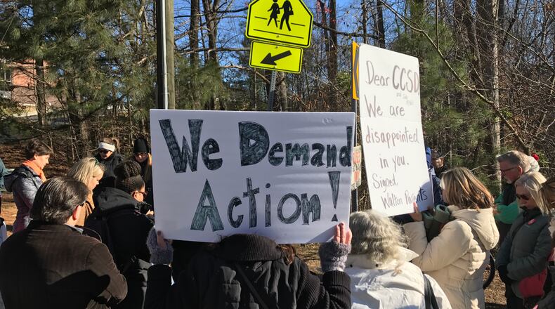 In Cobb County, a group of about 40 Walton High parents and community members observe a moment of silence outside the school at 10 a.m. while about 266 students walked out of school as part of a nationwide protest. VANESSA McCRAY / AJC