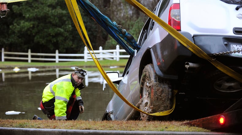 Officials help to remove an SUV that was submerged in a pond off Batesville Road in rural Cherokee County after a driver was rescued by firefighters near Atlanta National Golf Course early Monday morning, Dec. 29, 2014, in Canton.