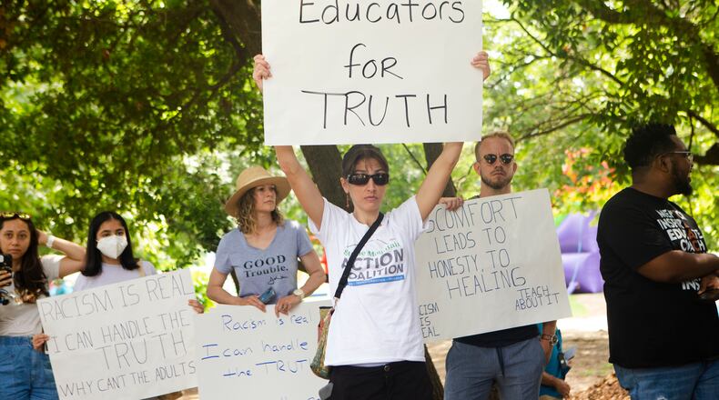 Sally Stanhope, a social studies teacher at Chamblee High School, holds up a homemade sign during a back-to-school rally for Georgia educators on Saturday, July 23, 2022, at Piedmont Park in Atlanta. Teachers, community members and students gathered to speak against new state legislative action banning selected books from school libraries and prohibiting the teaching of divisive concepts, which affected how race could be discussed in classrooms.  (Christina Matacotta for The Atlanta Journal-Constitution)