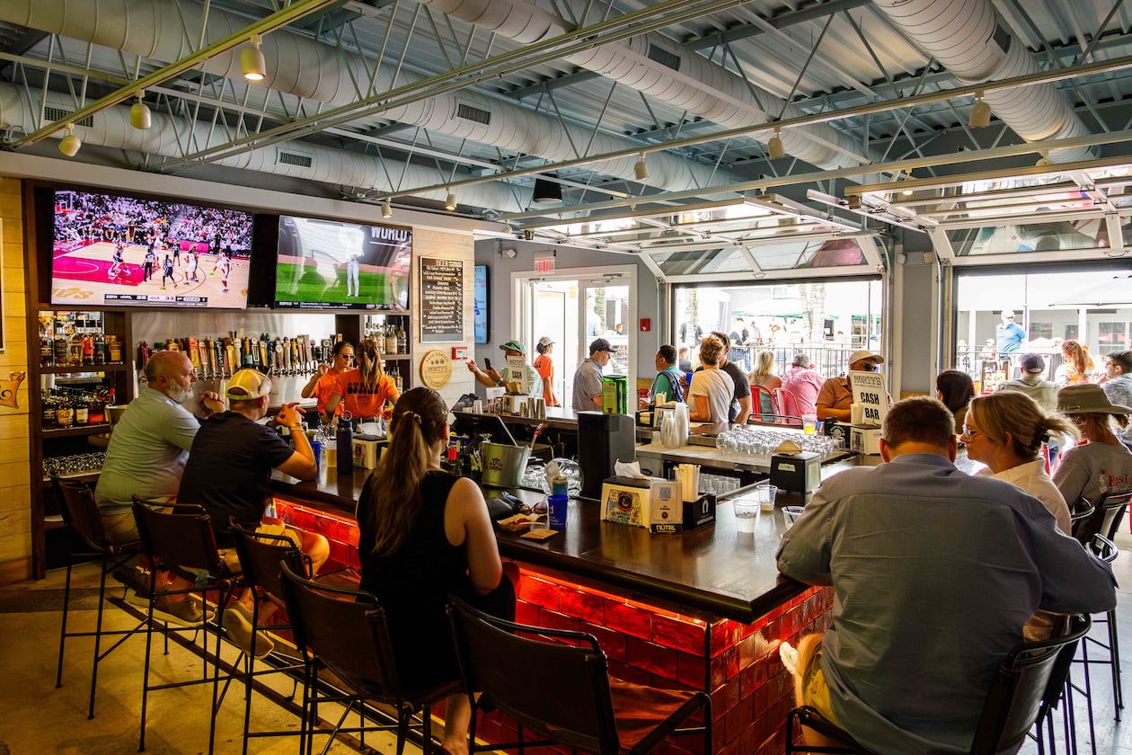 A busy horseshoe-shaped bar looks out onto a courtyard through rollup garage doors.