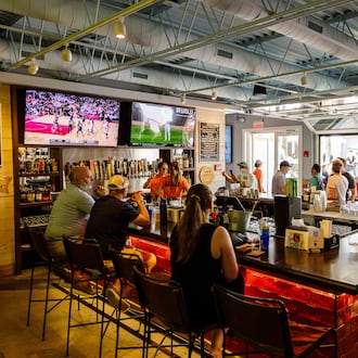 A busy horseshoe-shaped bar looks out onto a courtyard through rollup garage doors.