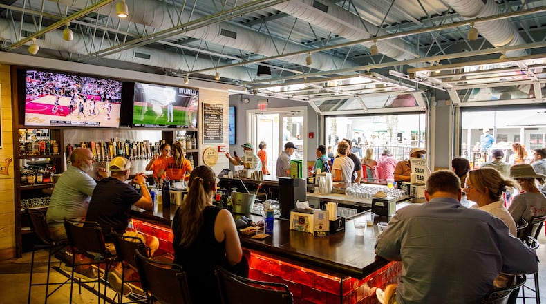 A busy horseshoe-shaped bar looks out onto a courtyard through rollup garage doors.
