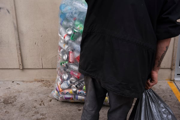 A person holds a bag of used beverage containers while waiting outside the Glisan BottleDrop Redemption Center on Thursday, May 15, 2025, in Portland, Ore. (AP Photo/Jenny Kane)