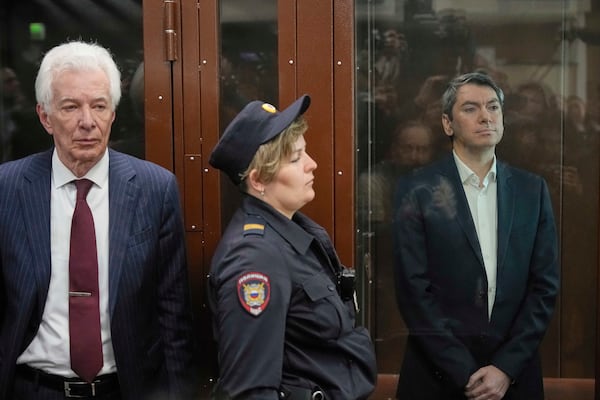 Grigory Melkonyants, right, co-chair of Russia's leading independent election monitoring group Golos who faces up to 5 years in prison, looks at the media standing in a cage in a courtroom prior to a hearing as Lawyer Mikhail Biryukov, stands near in Basmanny district court in Moscow, Russia, Wednesday, May 14, 2025. (AP Photo/Alexander Zemlianichenko)