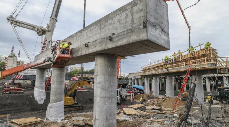Construction workers continued to reshape the I-85 bridge Monday, working high on the pillar supports as bridge beams were starting to arrive. JOHN SPINK/JSPINK@AJC.COM