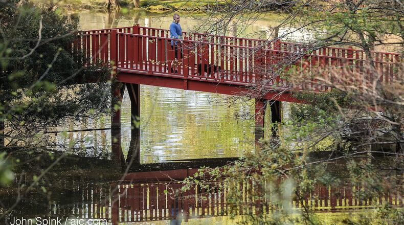 Cameron Powell walks his dog Emmitt in Lenox Park on Wednesday. JOHN SPINK / JSPINK@AJC.COM