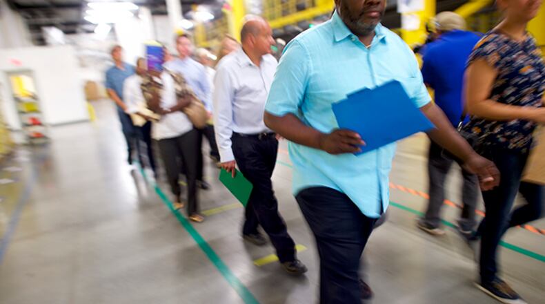 Job seekers tour the Amazon Fulfillment Center during an Amazon jobs fair on August 2, 2017 in Robbinsville, New Jersey. The American commerce company is hosting 'Amazon Jobs Day' with job fairs across the country to hire 50,000 positions for their fulfillment centers nationwide. The more than 1 million square foot facility holds tens of millions of products and features more than 14 miles of conveyor belts, employing more than 4,000 workers who pick, pack, and ship orders.