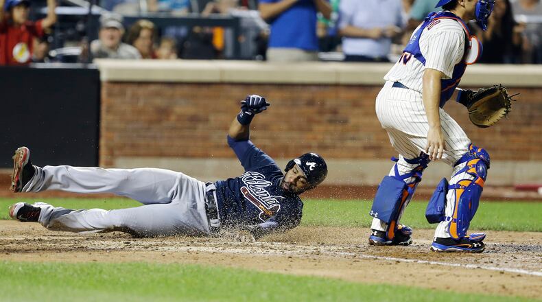 Atlanta Braves' Jason Heyward slides past New York Mets catcher Travis d'Arnaud to score on a double by Andrelton Simmons during the seventh inning of a baseball game Tuesday, Aug. 20, 2013, in New York. (AP Photo/Frank Franklin II)