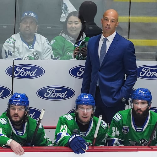 FILE -Abbotsford Canucks' head coach Manny Malhotra stands on the bench behind Sammy Blais, front left to right, Jonathan Lekkerimaki and Phillip Di Giuseppe during the first period in Game 5 of the AHL hockey Calder Cup Final against the Charlotte Checkers, in Abbotsford, British Columbia, June 21, 2025. (Darryl Dyck/The Canadian Press via AP, File)