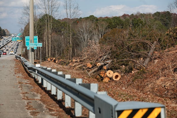 Piles of cut trees lie along the side of Ga. 400 near Exit 7 in Roswell. The trees are being removed ahead of construction on new express lanes along the highway. (Natrice Miller/AJC)