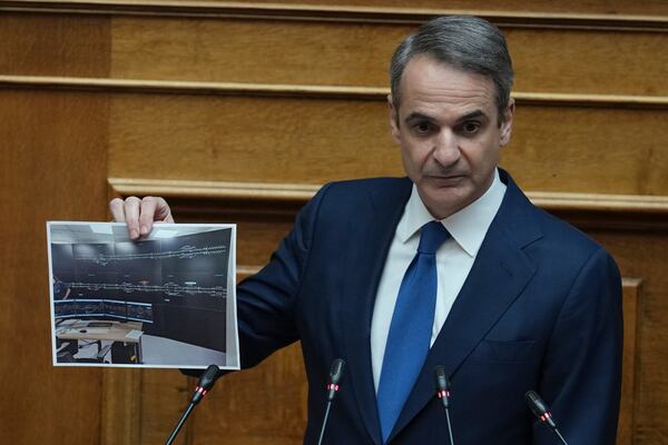 Greek Prime Minister Kyriakos Mitsotakis holds up a photograph of a new railway control facility during his speech in parliament, ahead of the submission of a no-confidence motion by opposition parties over the government's handling of Greece's worst rail disaster two year ago, in Athens, Wednesday, March 5, 2025. (AP Photo/Thanassis Stavrakis)