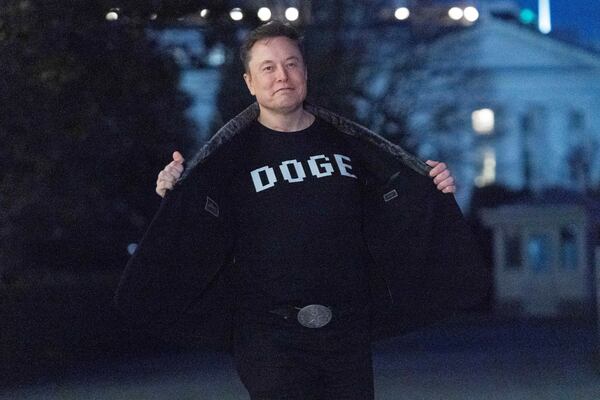 FILE - Elon Musk flashes his t-shirt that reads "DOGE" to the media as he walks on South Lawn of the White House, in Washington, March 9, 2025. (AP Photo/Jose Luis Magana, File)