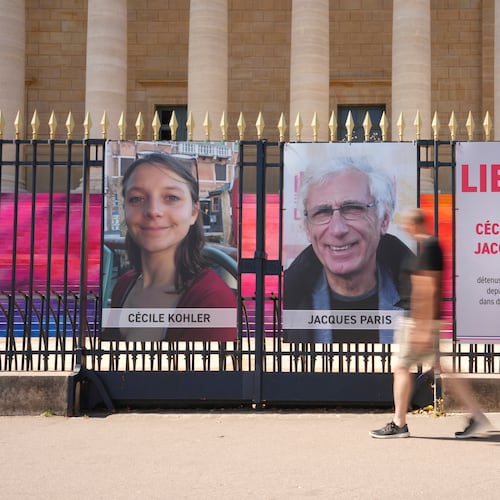 FILE - People walk past the portraits of French nationals Cecile Kohler and Jacques Paris in front of the French National Assembly in Paris on July 3, 2025. (AP Photo/Aurelien Morissard, File)