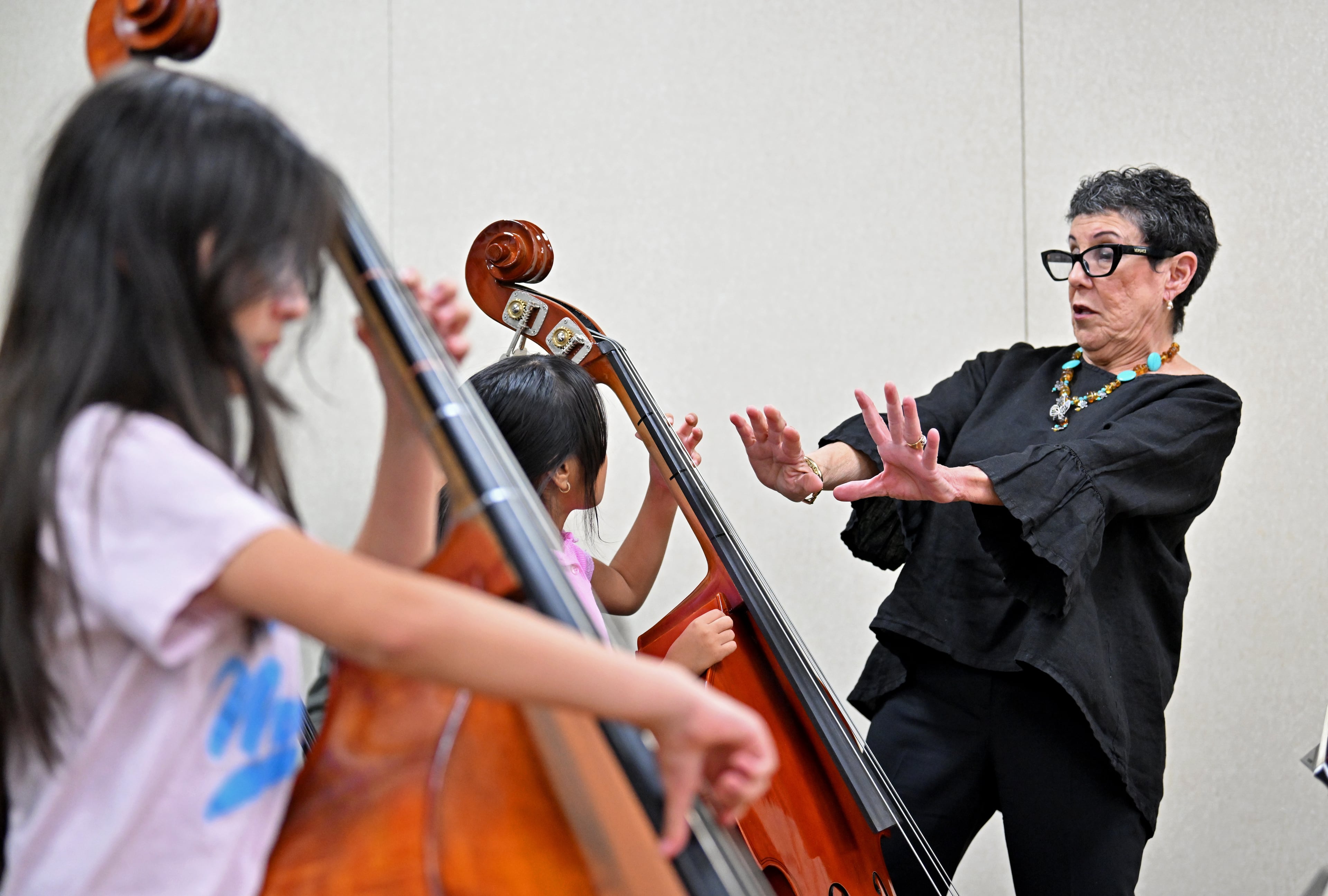 Juana Alzaga (standing), pictured instructing orchestra members on Thursday, Nov. 6, 2025, has high expectations for her students: “Excellence is what I’m all about. I require it from me, and I require it from the kids.” (Hyosub Shin/AJC)