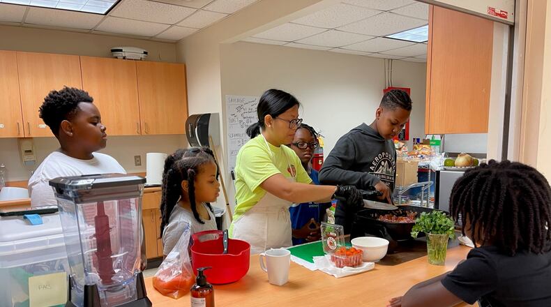 Cecilia Tran (center, in green), with the UGA Extension service, teaches campers how to make tacos at a 2023 summer camp. This year Tran, a registered dietitian, is running Let Them Cook, a new summer camp on teaching cooking skills.