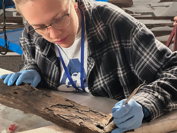 Research assistant Marissa Agerton cleans a piece of wood from a Revolutionary War-era gunboat to prepare for the craft's partial reconstruction at the New York State Museum, Friday, May 30, 2025, in Albany, New York. (AP Photo/Michael Hill)