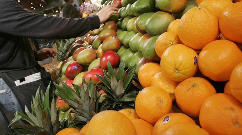 A grocer arranges mangoes in the produce section at Whole Foods January 13, 2005 in New York City. (Photo by Stephen Chernin/Getty Images)