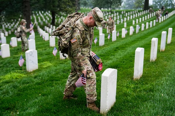 Members of the military place U.S. flags by headstones at Arlington National Cemetery in Virginia ahead of Memorial Day.
