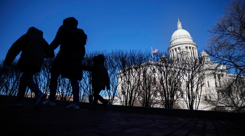 FILE - Pedestrians walk past the Rhode Island Statehouse, March 1, 2020, in Providence, R.I. (AP Photo/David Goldman, File)