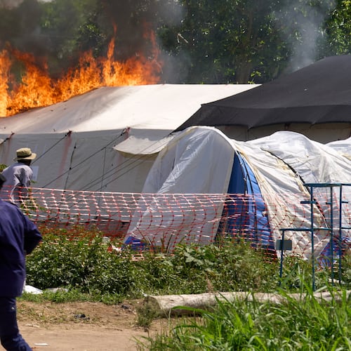 A security guard runs in front of an Ebola treatment center in flames in Rwampara, Congo, Thursday, May 21, 2026. (AP Photo/Dirole Lotsima Dieudonne)