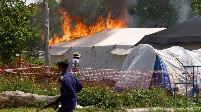 A security guard runs in front of an Ebola treatment center in flames in Rwampara, Congo, Thursday, May 21, 2026. (AP Photo/Dirole Lotsima Dieudonne)