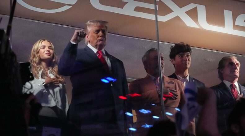 President Donald Trump gestures during the National Anthem as he attends an NBA Finals playoff basketball game between the New York Knicks and the San Antonio Spurs at Madison Square Garden in New York, Monday, June 8, 2026, with Kai Trump, left, Knicks owner James Dolan and Interior Secretary Doug Burgum, right. (AP Photo/Mark Schiefelbein)