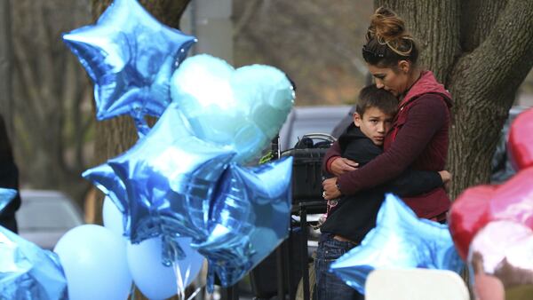 A woman and child hug near a memorial outside the home of 5-year-old Andrew "AJ" Freund Wednesday, April 24, 2019, in Crystal Lake, Ill. AJ's parents, JoAnn Cunningham, 36, and Andrew Freund Sr., 60, face multiple charges, including five counts of first-degree murder, in the boy's death. AJ was reported missing from the family's home Thursday, April 18, 2019. His body was found wrapped in plastic and buried in a shallow grave six days later near Woodstock.