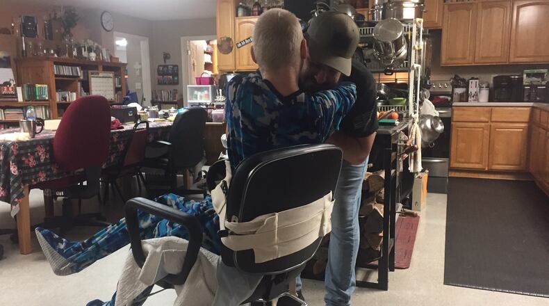 Logan Fahey, the biological son of the founders of The King's Cleft ministry, hugs Jayden Fahey, 21, on Thursday while he is strapped to a chair for his own protection. Jayden has Angelman syndrome, a genetic disorder. (Johnny Edwards / Johnny.Edwards@ajc.com)