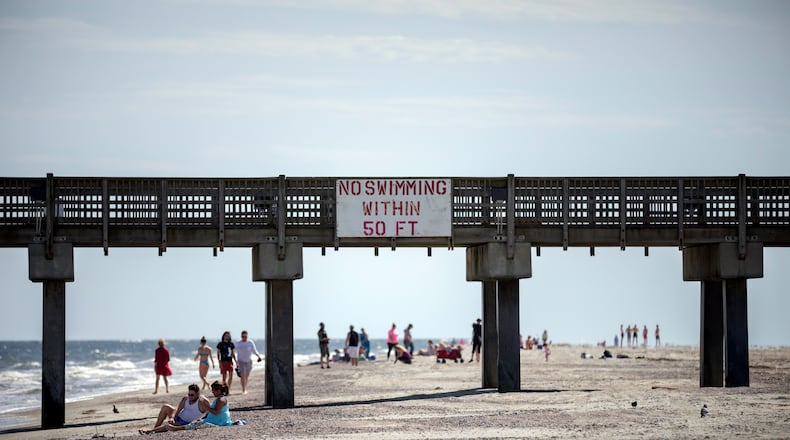 TYBEE ISLAND, GA - APRIL 4, 2020: People walk along Tybee Island's beach near the Tybee Pier at low tide after Gov. Brian Kemp signed an executive order allowing people to exercise outside, with social distancing of at least 6 feet. (AJC Photo/Stephen B. Morton)