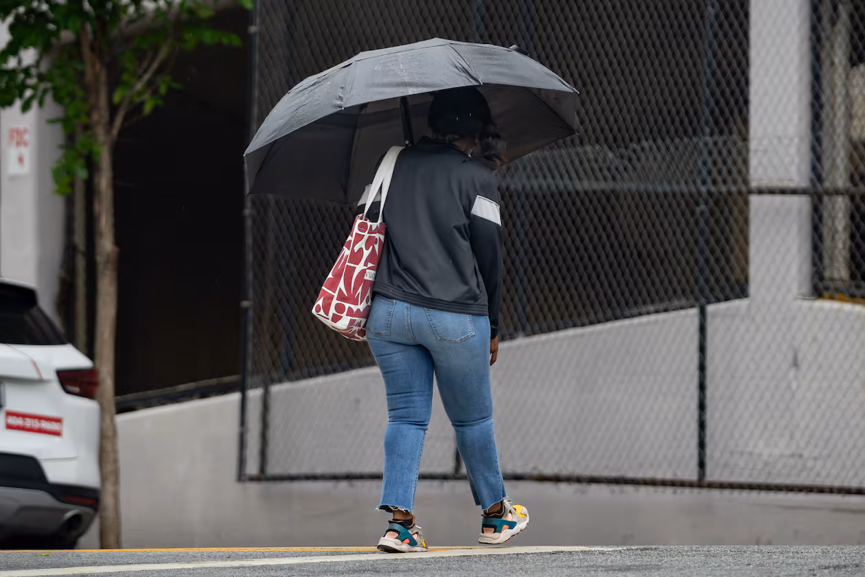 A woman with an umbrella crosses Cone Street in Atlanta during light rain on Friday, May 29, 2026. (Ben Hendren for the AJC)