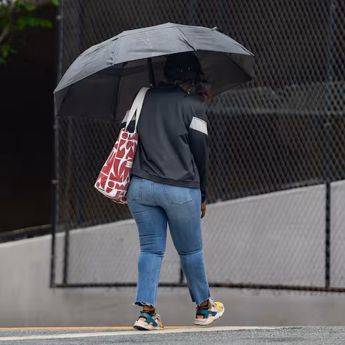 A woman with an umbrella crosses Cone Street in Atlanta during light rain on Friday, May 29, 2026. (Ben Hendren for the AJC)