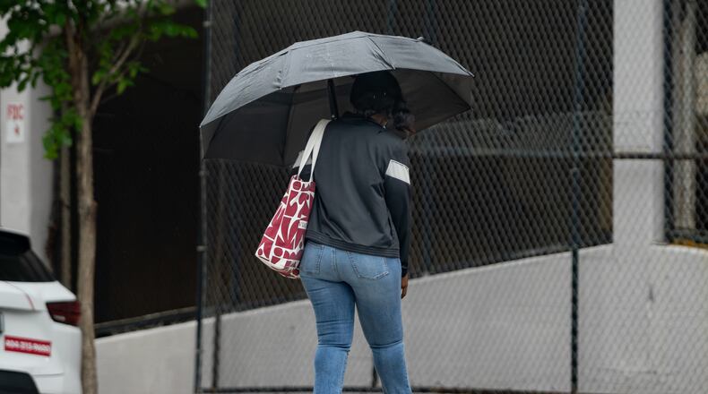 A woman with an umbrella crosses Cone Street in Atlanta during light rain on Friday, May 29, 2026. (Ben Hendren for the AJC)