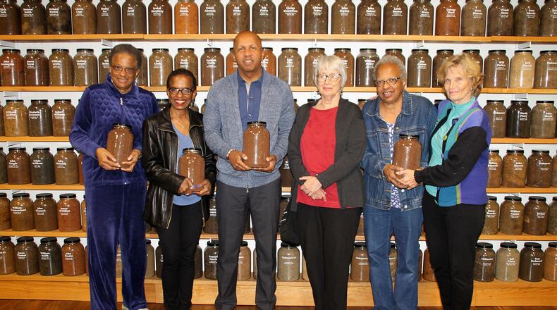 The author, Karen Branan, third from right, with Equal Justice Initiative director Bryan Stevenson and, from left, Jackie Jordan Irvine, Angela Jordan Davis, Jennifer Jordan and Branan’s sister, Barbara Williams. They are holding jars of soil taken from the sites of lynchings. (Deborah Daniels Dawson / for the AJC)
