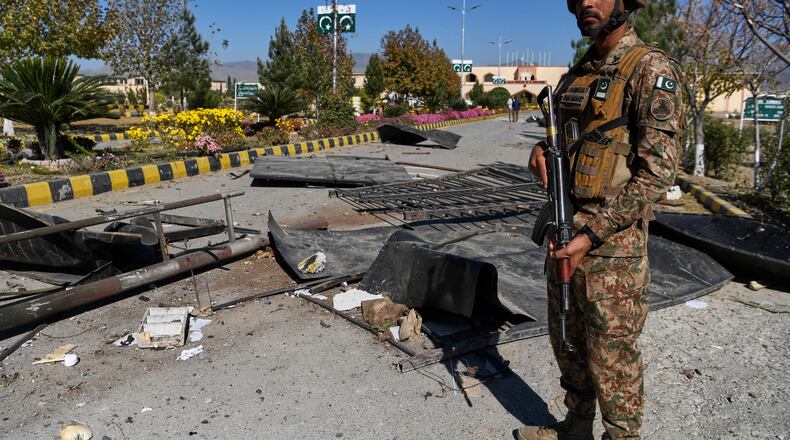 An Army soldier stands guard next to damages at the main gate of an army-run cadet college that was assaulted by militants on Monday, in Wana, a city in the northwestern Pakistani district South Waziristan bordering with Afghanistan, Thursday, Nov. 13, 2025. (AP Photo/Ahsan Shahzad)