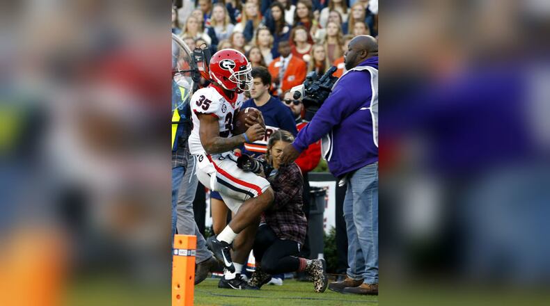 Georgia running back Brian Herrien (35) runs out of bounds and into a photographer during the first half of an NCAA college football game against Auburn, Saturday, Nov. 16, 2019, in Auburn, Ala.