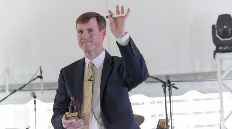Cox Washington bureau radio reporter Jamie Dupree waves to the audience at a Town Hall meeting of Cox Enterprises employees. Dupree holds in his right hand the Governor Cox Award, which he was presented at the meeting. CONTRIBUTED