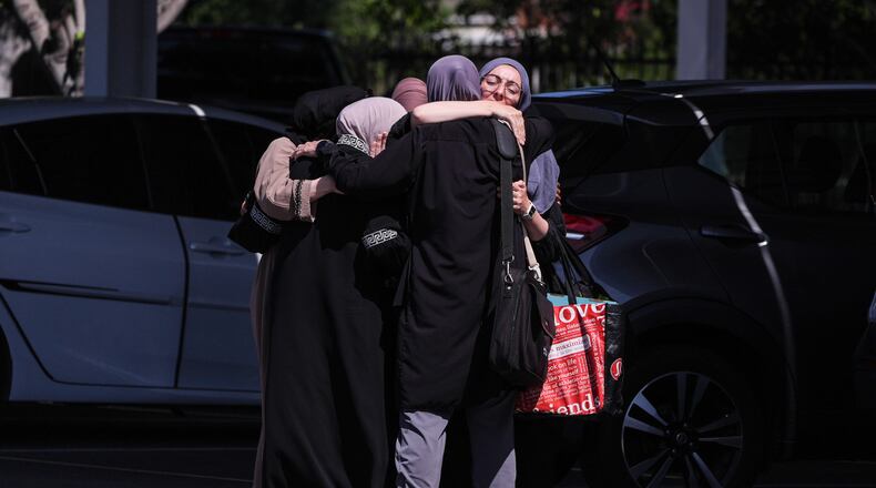 People embrace outside of the Islamic Center of San Diego, a day after a shooting, Tuesday, May 19, 2026, in San Diego. (AP Photo/Jae C. Hong)