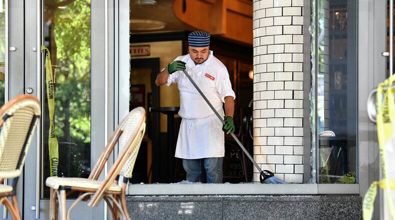 An employee of Bistro Niko restaurant on Peachtree Road in Buckhead cleans up Saturday after a night of vandalism and looting in the area that followed the first day of protests in downtown Atlanta. Buckhead leaders estimate damages along a four-mile stretch of the north Atlanta community at about $10 million to $15 million. PHOTO: HYOSUB SHIN/Hyosub.Shin@ajc.com)