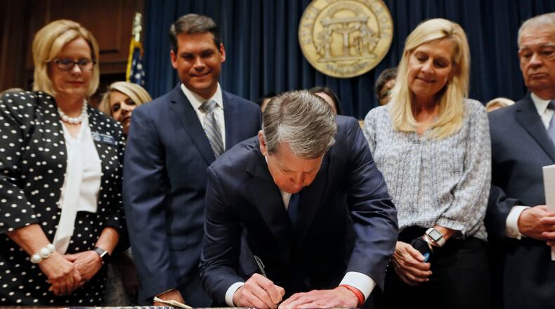 Surrounded by supporters of the bill, including state Sen. Renee Unterman (from left), R - Buford, Lt. Gov. Geoff Duncan, first lady Marty Kemp, and House Speaker David Ralston, Gov. Brian Kemp puts his signature to HB 481, the anti-abortion "heartbeat bill" in May. Bob Andres / bandres@ajc.com
