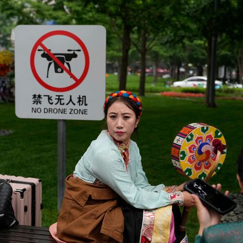 A performer rests near a "No Drone Zone" sign in Beijing, on May 31, 2023. (AP Photo/Ng Han Guan)