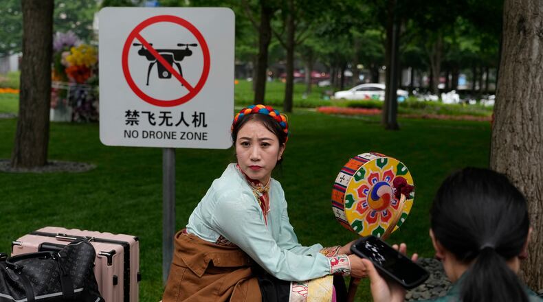 A performer rests near a "No Drone Zone" sign in Beijing, on May 31, 2023. (AP Photo/Ng Han Guan)
