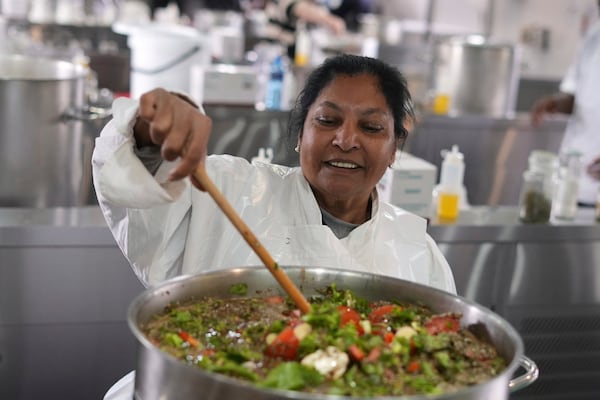 A woman from a local charity steering a pot with nutritional, as chefs, caterers, and culinary students joined forces to whip together 67,000 litres of soup in celebration of Nelson Mandela Day in Johannesburg, South Africa, Friday, July 18, 2025. (AP Photo/Alfonso Nqunjana)