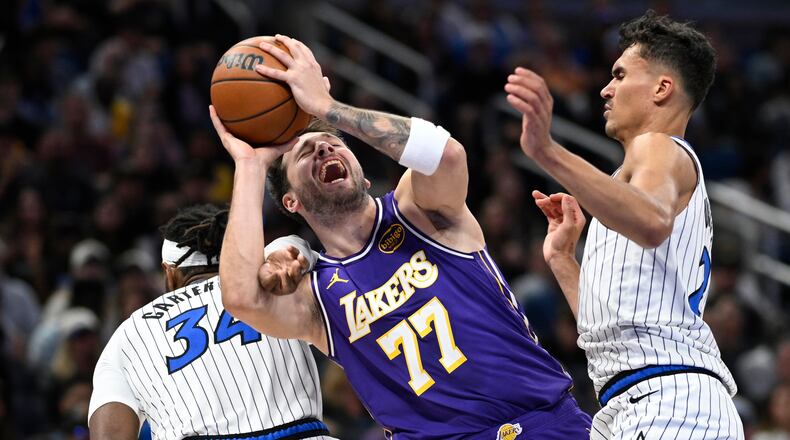 Los Angeles Lakers guard Luka Doncic (77) is fouled by Orlando Magic center Wendell Carter Jr. (34) as Magic forward Tristan da Silva, right, helps defend during the first half of an NBA basketball game, Saturday, March 21, 2026, in Orlando, Fla. (AP Photo/Phelan M. Ebenhack)