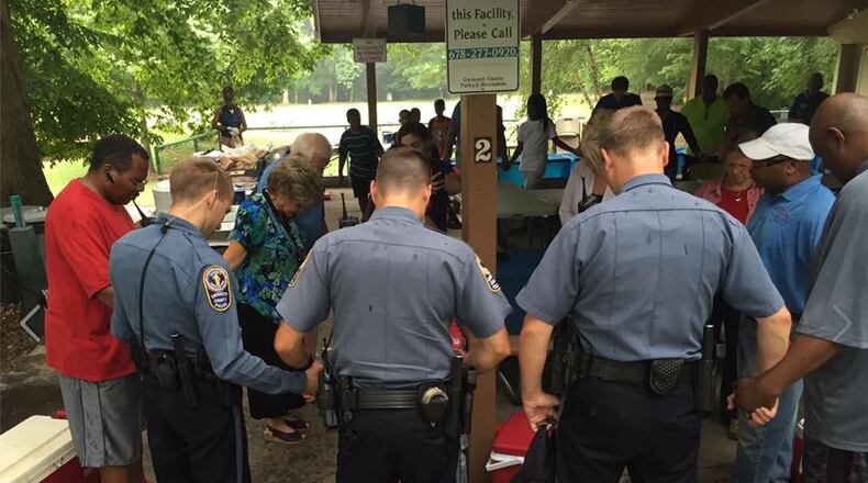 Peachtree Corners residents pray for police officers at a recent picnic at Jones Bridge Park. Bridges Peachtree Corners seeks to promote understanding among people of all races.