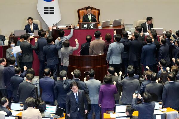 FILE - South Korea's opposition Democratic Party leader Lee Jae-myung, bottom center, walks past lawmakers of the ruling People Power Party protesting to South Korea's National Assembly Speaker Woo Won Shik, top center, during a plenary session for the impeachment motion against South Korean acting President Han Duck-soo at the National Assembly in Seoul, South Korea, on Dec. 27, 2024. (AP Photo/Ahn Young-joon, File)