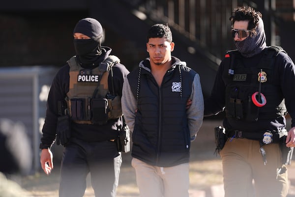 FILE - Law officials escort a suspect from an apartment to a waiting utility vehicle for transport during a raid Wednesday, Feb. 5, 2025, in east Denver. (AP Photo/David Zalubowski, File)