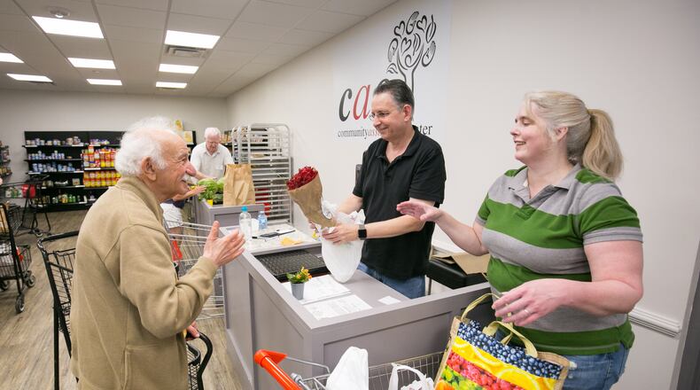 On the north end of Sandy Springs, in 2018, Community Assistance Center volunteers Mort Epstein, center, and Lori Proctor, right, help customer Alexander Boguslavskiy checks out at the food pantry. (JASON GETZ/SPECIAL TO THE AJC)