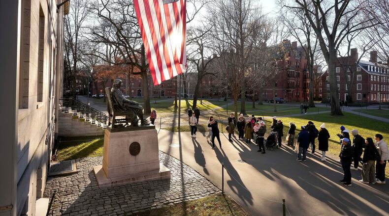 FILE - People take photos near a John Harvard statue, left, on the Harvard University campus, Jan. 2, 2024, in Cambridge, Mass. (AP Photo/Steven Senne, File)
