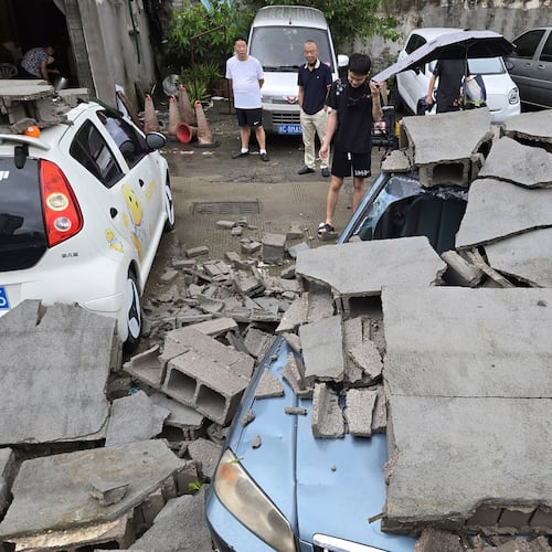 Residents view cars damaged by a fallen wall in the aftermath of Typhoon Dolphin in Wenzhou in eastern China's Zhejiang province, Monday, Aug. 10, 2026. (Chinatopix via AP)